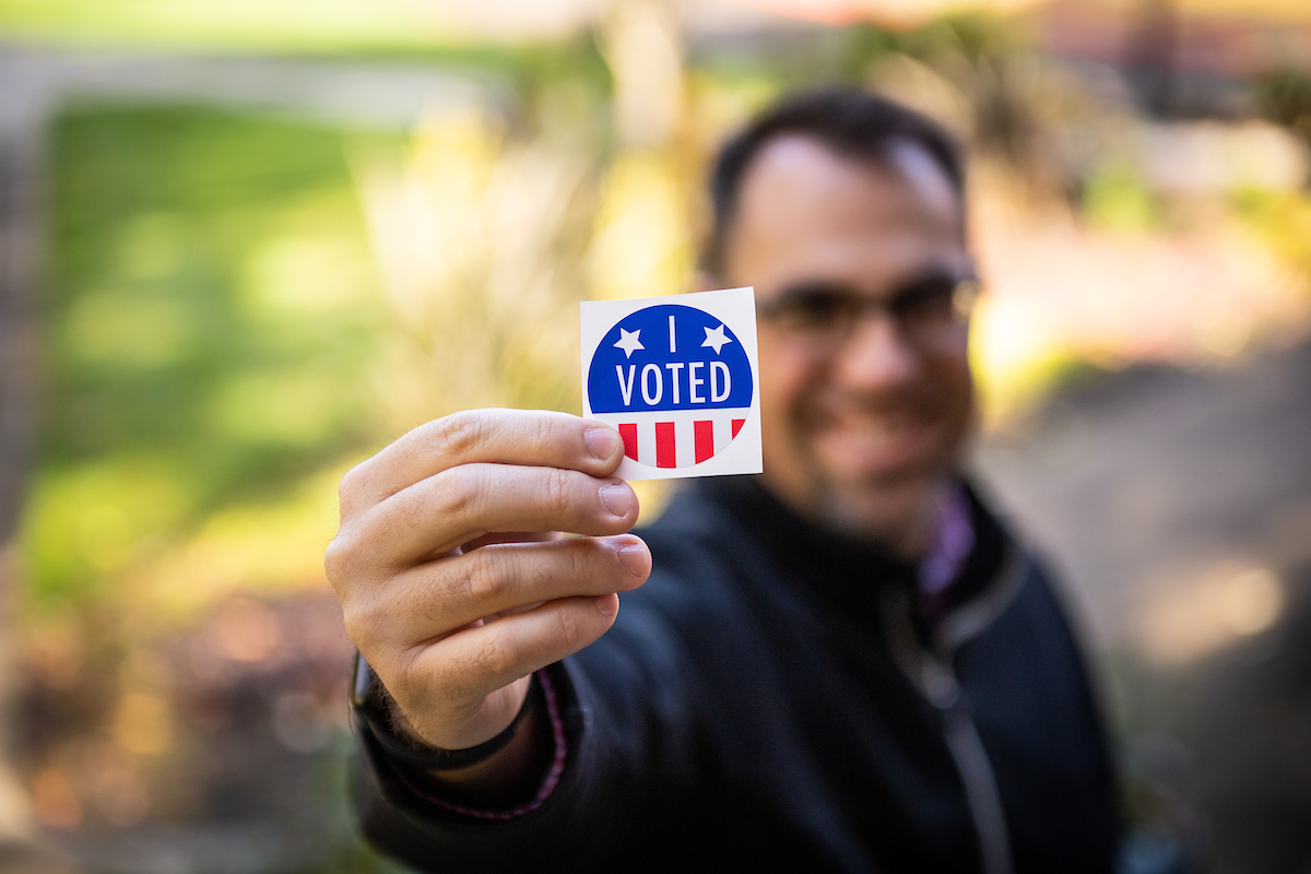 ѨƵ community member holding up a "Vote!" sticker.